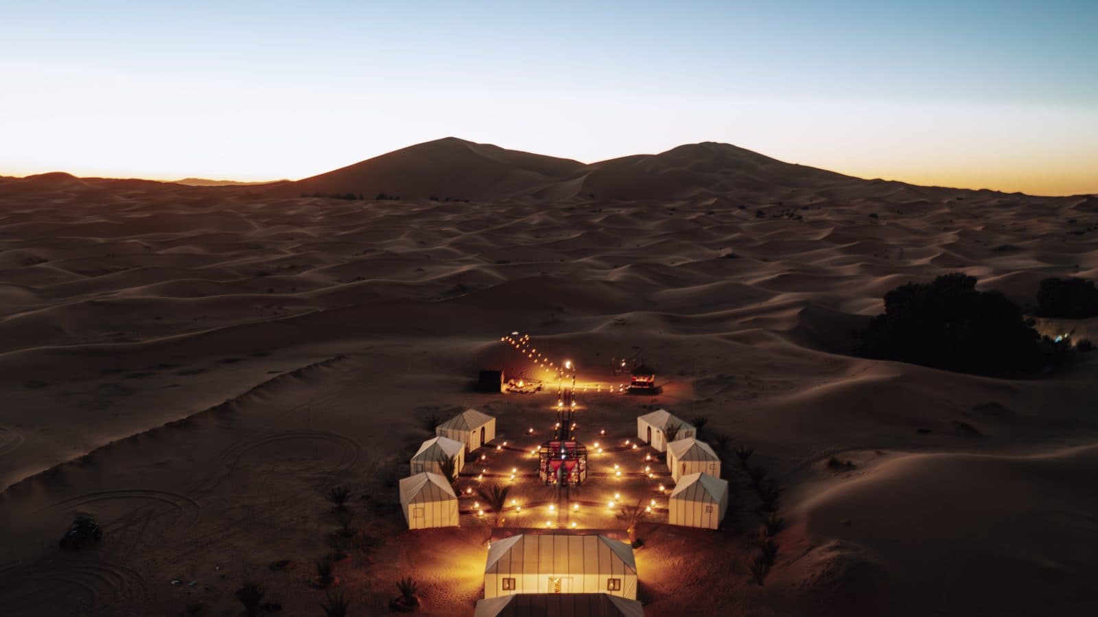 Tiziri Camp's eight tents lit at dusk in the Erg Chebbi dunes