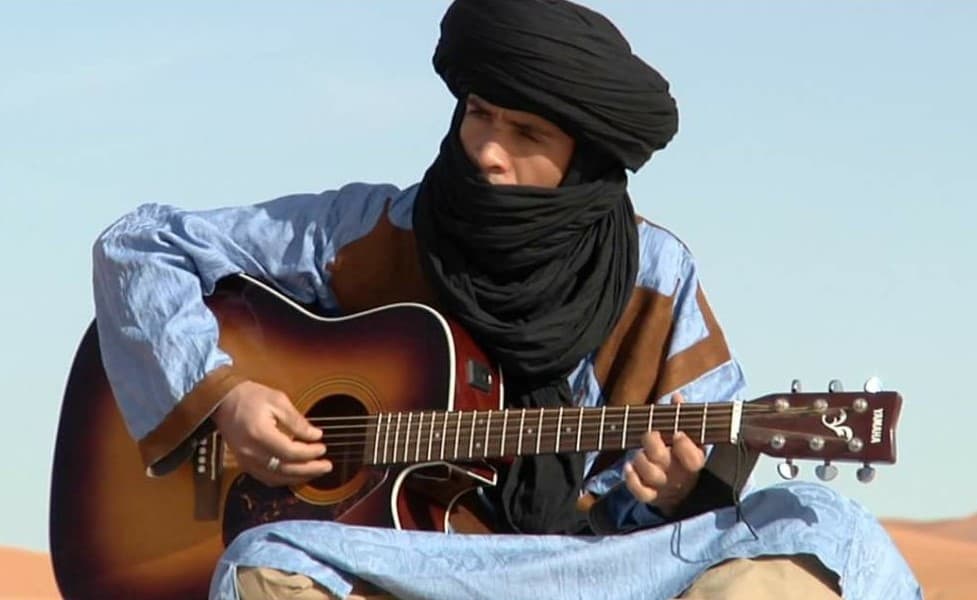 Hmad, founder of Tiziri Camp, playing guitar in the Erg Chebbi dunes